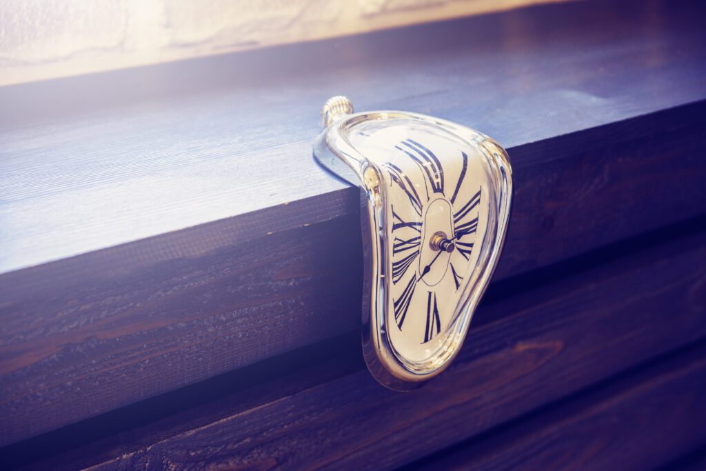 Indoor clocks of unusual shape on a brown wooden background Time flows